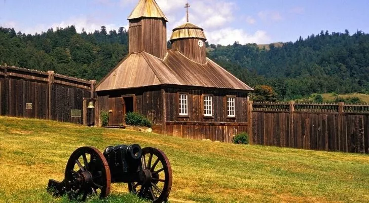 Fort Ross in California with a canon wagon on a field and the fort behind