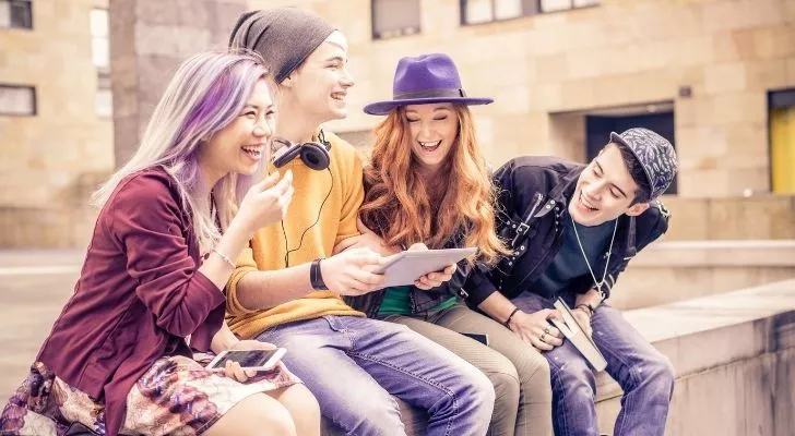 Friends laughing while sitting on a wall