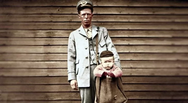 US Postal Service worker holding with a toddler in his mail bag