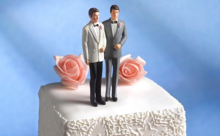 Two grooms on top of a cake