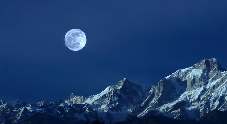 The bright Cold Moon above snow topped mountains