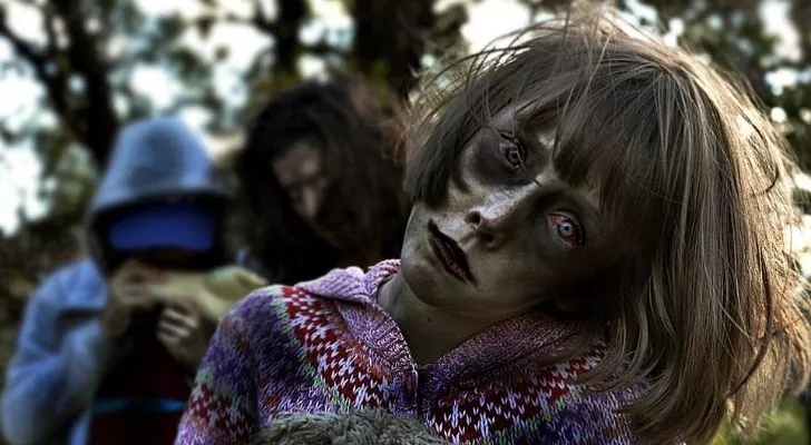 A young zombie girl with her head tilted to one side