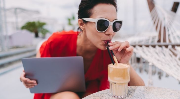 Una mujer bebe un frappé mientras trabaja en su iPad