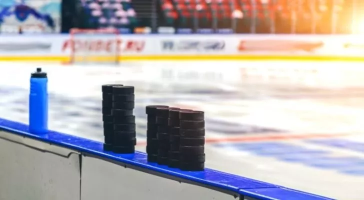 A pile of hockey pucks at the side of the ice rink.