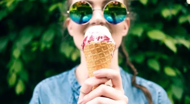 Person holding a cone with two scoops of ice cream