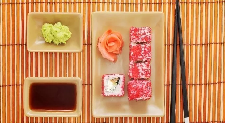 A plate of sushi with wasabi and soy sauce on the side.