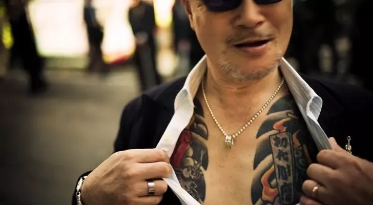 A Yakuza showing off his chest tattoos.
