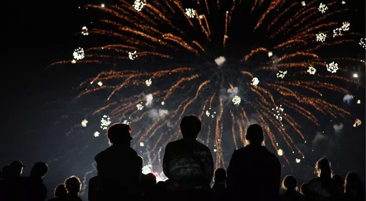 A group of people seated and watching fireworks.