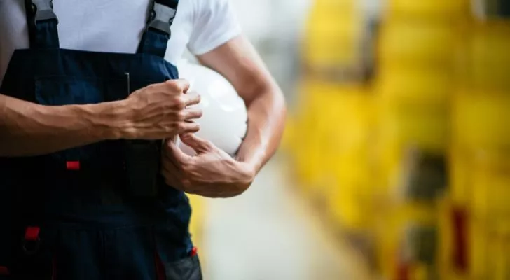 A factory worker holding their protective gear. 