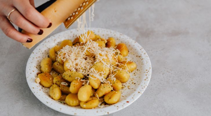Parmesan being grated onto gnocchi