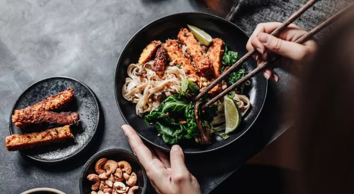 Someone eating food from a bowl using chopsticks