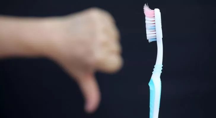 An old used toothbrush and someone with a thumbs down