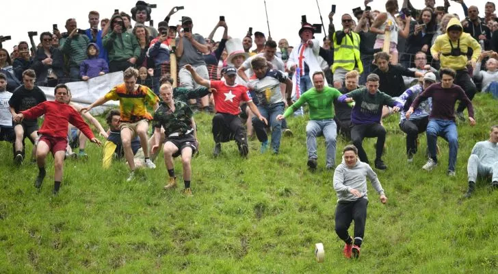 Njerëz që marrin pjesë në sportin e rrotullimit të djathit në Angli.