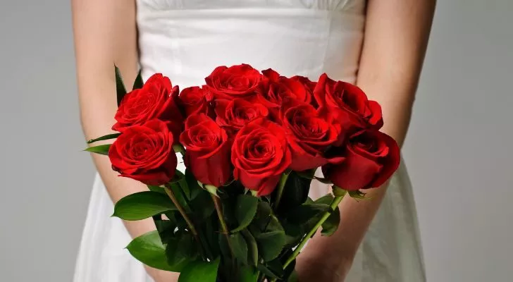 Someone holding a dozen red roses