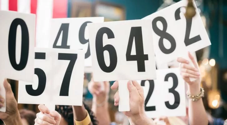 Many hands holding up auction bid cards