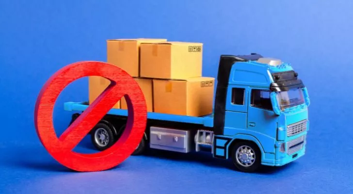 A truck with boxes, and a red circled with a diagonal strike through it representing something being banned