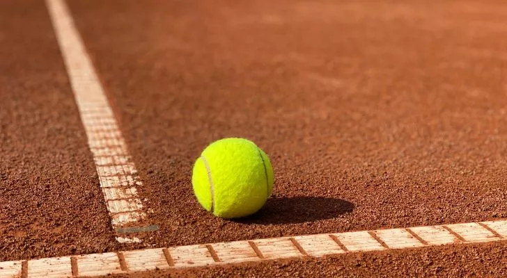 A tennis ball on a clay tennis court.