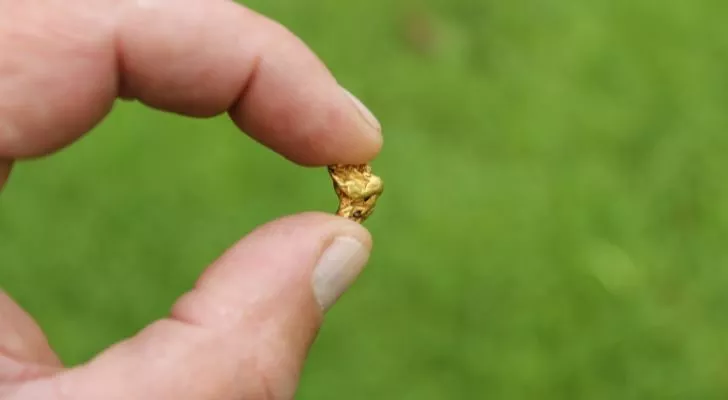 A gold nugget held between thumb and forefinger