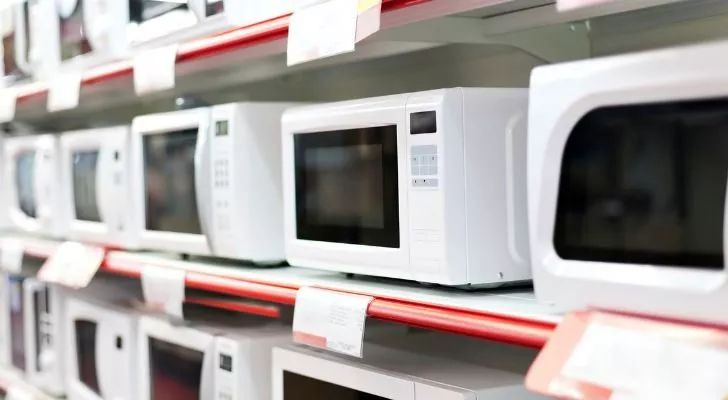 Shelves full of white microwaves for sale at a department store.
