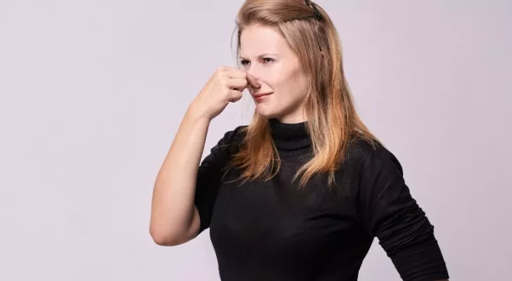 A women holding her nose as she smells something bad