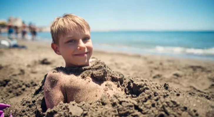 A child who has been buried in the sand by his friends
