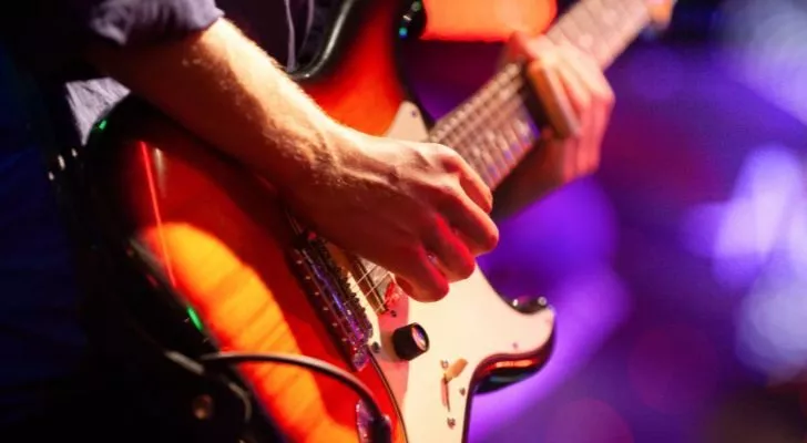 A man's hands strumming on an electric guitar