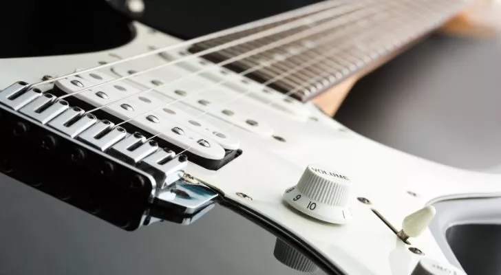 A close up of an electric guitar's strings and pickup