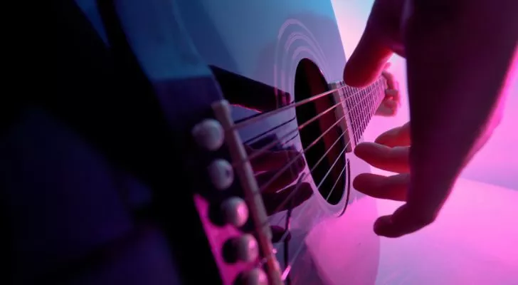 A close up of a hand plucking guitar strings