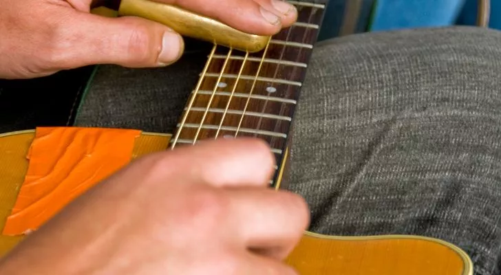 A guitar rests on someone's lap as they play it