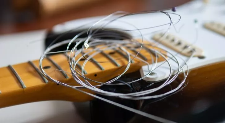 Some guitar strings rest on top of an unstrung guitar