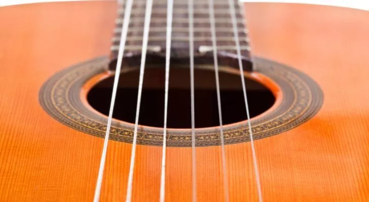 A guitar's soundhole and the six strings that stretch over it