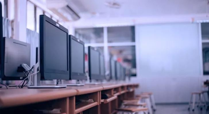 A row of computer screens in a school classroom