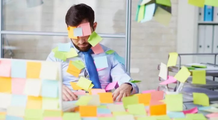 A man and his office completely covered in sticky notes