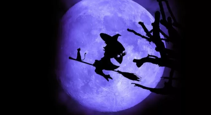A witch's silhouette against a full moon