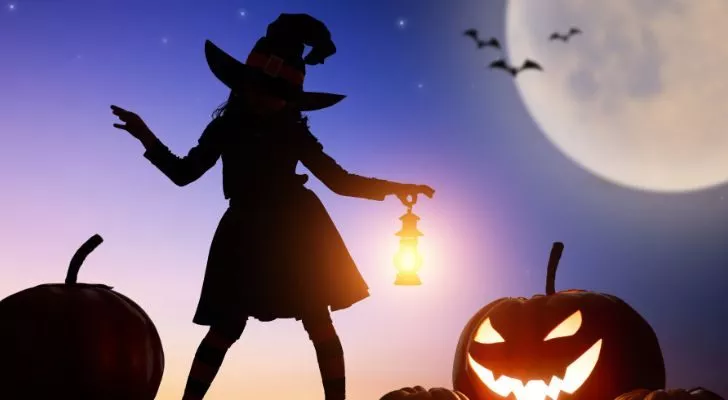 A witch's silhouette next to a Jack o' lantern with the moon in the background