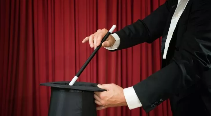 A magician performs a magic trick with a wand and a hat