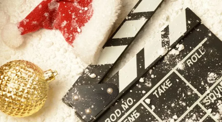 A clapboard lies in snow alongside festive ornaments