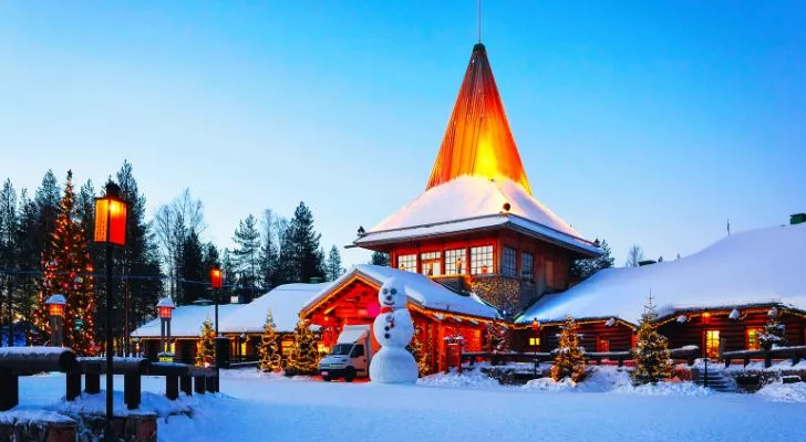 A snow covered building with a snowman in front