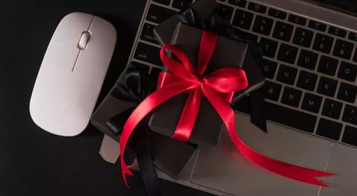A wireless mouse sits next to a laptop which has a small gift placed on its keyboard
