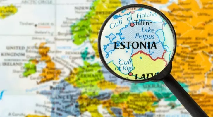 A magnifying glass held over a map of Europe, highlighting Estonia