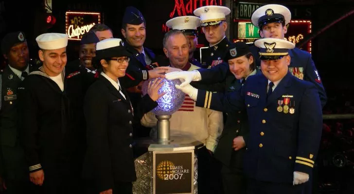 Several members of the Navy lean in to all press the ball drop button together