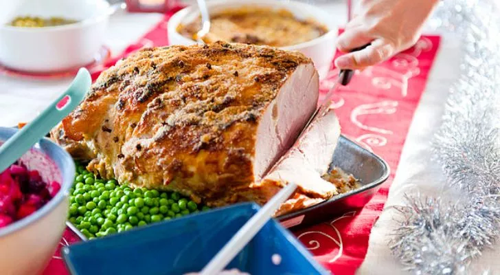 A thick chunk of ham being served as part of a Christmas dinner