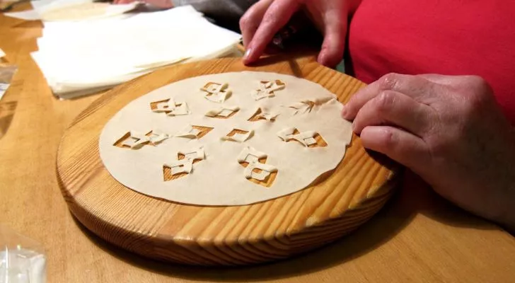 A thin bread with intricate shapes cut into it on a chopping board