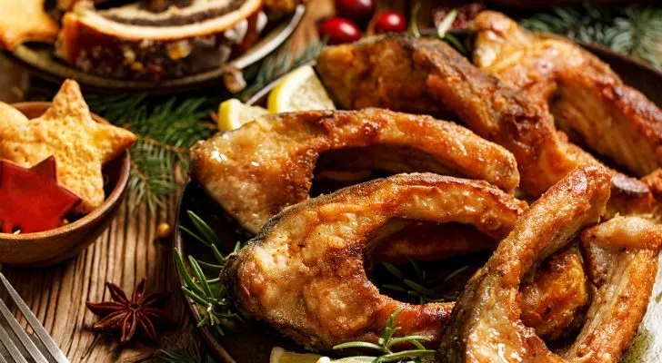 Slices of fried fish with lemon are served alongside other Christmas fare