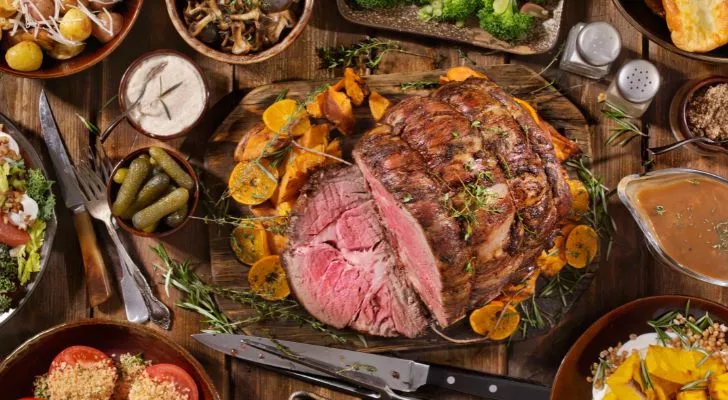 A huge feast is laid on a table with various meats and vegetables