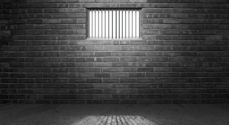 Sunlight creeps into a prison cell through a window with bars