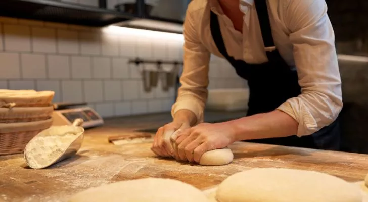 A person kneading bread in a bakery