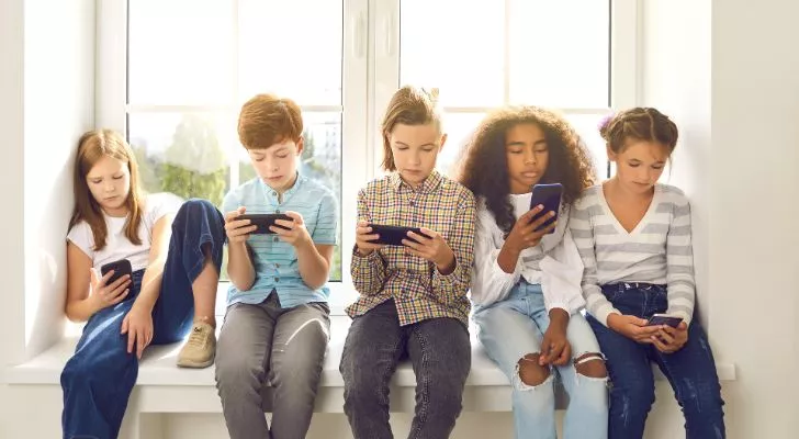 A group of young children looking at their smartphones