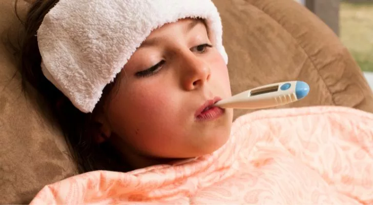 A child in bed with a thermometer in their mouth