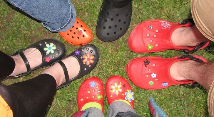 5 people wearing crocs putting their feet together in a circle